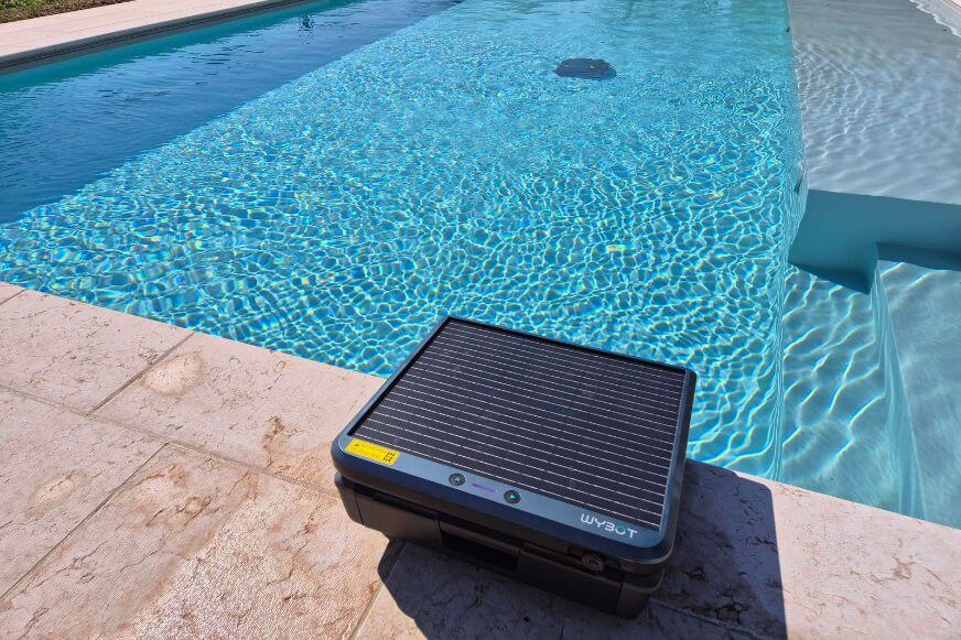 WYBOT S3 Solar-Kit im Vordergrund und Poolroboter im Einsatz im Hintergrund. Solarladung und autonome Reinigung gleichzeitig.